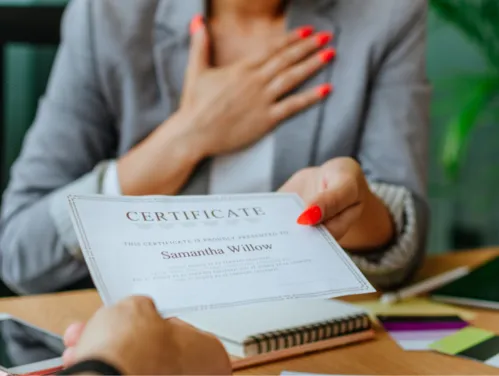 close-up photo of a person accepting a certificate while holding a hand over their heart