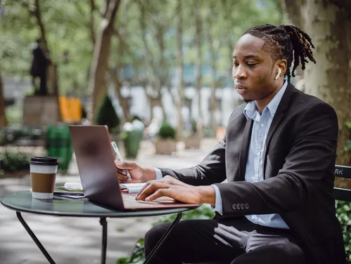 man sitting outside looking at laptop