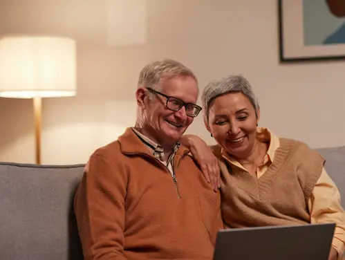 mature couple smiling and looking at a laptop