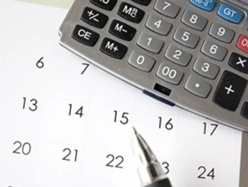 close-up photo of a calendar with a calculator and a pen