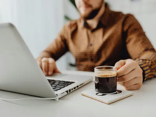 man looking a laptop with coffee
