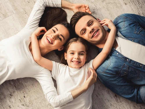 parents and a child laying on floor with heads next to each other