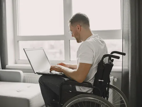 man in wheelchair looking at a laptop