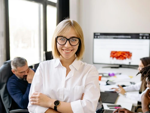 professional woman in white blouse with arms crossed in office setting