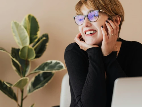 Woman with short hair and glasses smiling and looking away