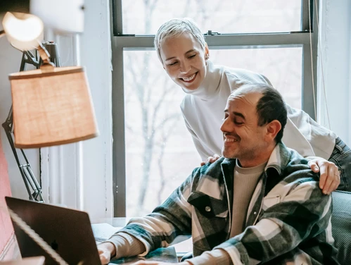 Mature couple looking at a laptop at home next to a window