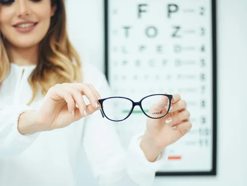 woman holding glasses at eye doctor office