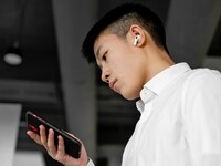 young male in white shirt looking at cell phone