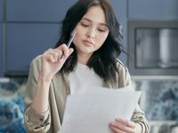 woman looking at a paper holding a pen in her hand