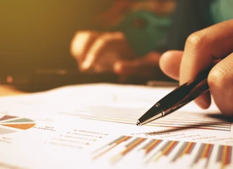 someone holding a pen over graphs on a paper