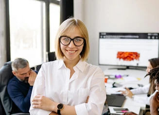 professional woman in white blouse with arms crossed in office setting