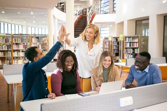 Team of diverse employees working, manager high-fiving one employee