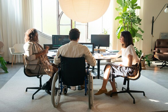 Three employees around a table, one in a wheelchair
